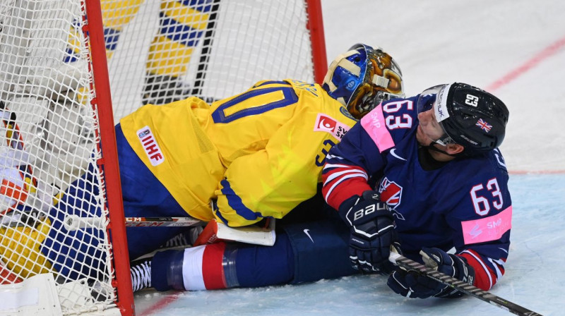 Lielbritānijas izlases hokejists Brendans Konolijs ietriecies Zviedrijas vārtsargā Viktorā Fāstā. Foto: Gints Ivuškāns/AFP/Scanpix