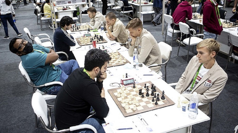 Latvijas šahisti (baltajos uzvalkos) pret Hondurasas komandu.   Foto no chessolympiad.fide.com